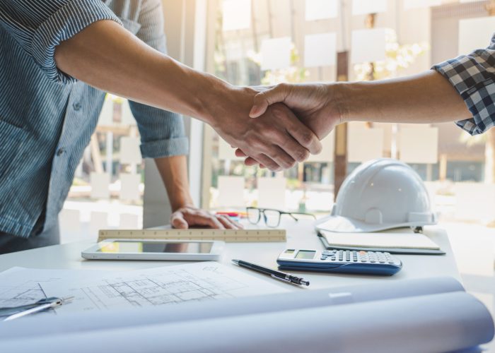 Architect and engineer construction workers shaking hands while working for teamwork and cooperation concept after finish an agreement in the office construction site, success collaboration concept